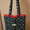Bolsa tote de lona estampada con margaritas blancas sobre azul marino. Bolso de hombro grande y resistente con cremallera roja. Estilo casual y vintage.