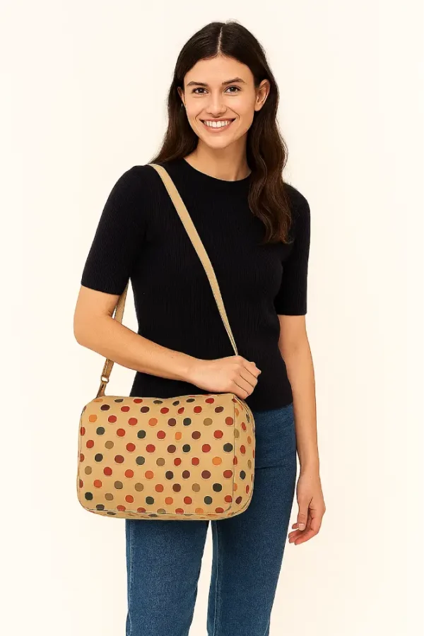 Bolso bandolera de tamaño medio con lunares de colores sobre fondo beige y cremallera frontal. Bolso cruzado de lona para uso diario. Estilo casual, divertido y original.