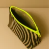 Neceser con estampado animal print de cebra (negro/beige). Neceser de viaje o maquillaje con cremallera neón flúor. Estuche organizador compacto y moderno.