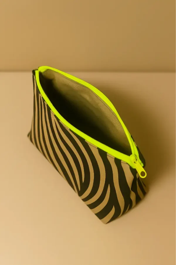 Neceser con estampado animal print de cebra (negro/beige). Neceser de viaje o maquillaje con cremallera neón flúor. Estuche organizador compacto y moderno.