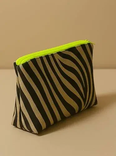 Neceser con estampado animal print de cebra (negro/beige). Neceser de viaje o maquillaje con cremallera neón flúor. Estuche organizador compacto y moderno.